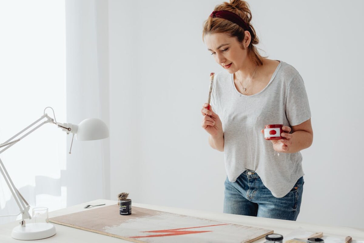 A woman engaged in painting with red paint in a contemporary indoor setting.
